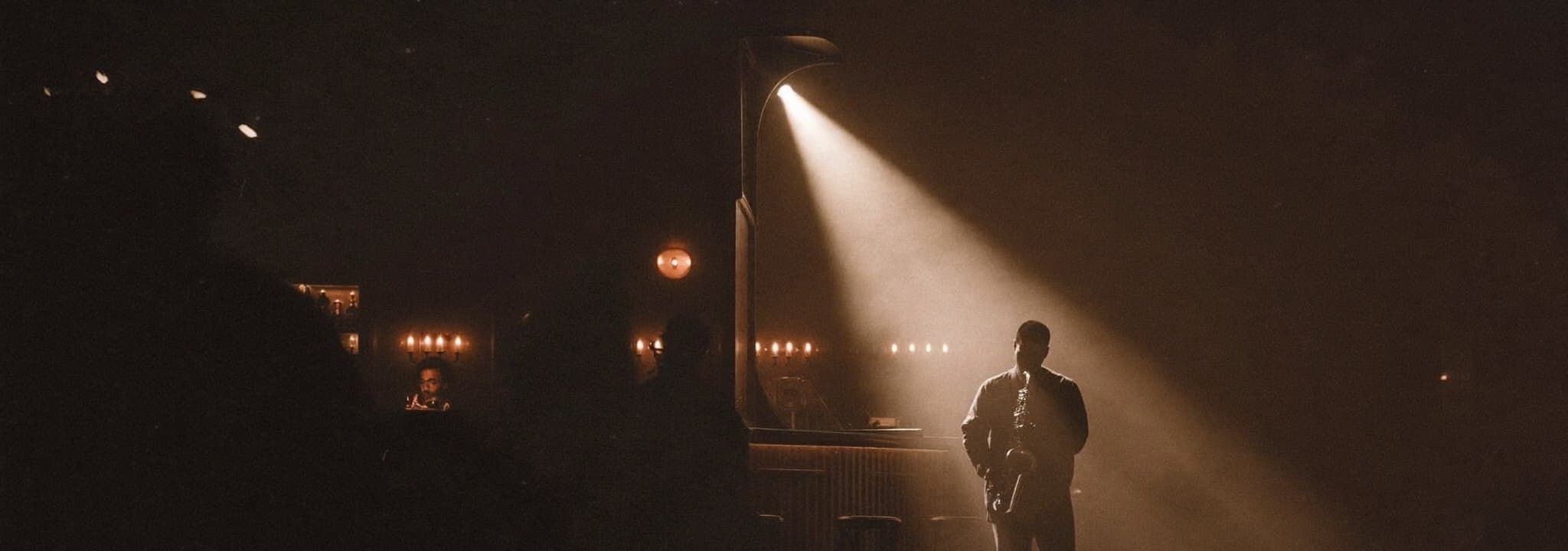 A saxophone player picked out by a single spotlight in a dark bar